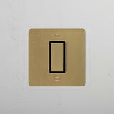 1G Centre Retractive Rocker Switch in Antique Brass Black on a white wall, part of 1G Switches & Dimmers.