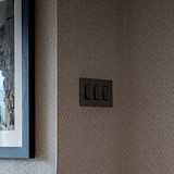3G Two Way Rocker Switch - Bronze Black, mounted on wall, complements modern decor.