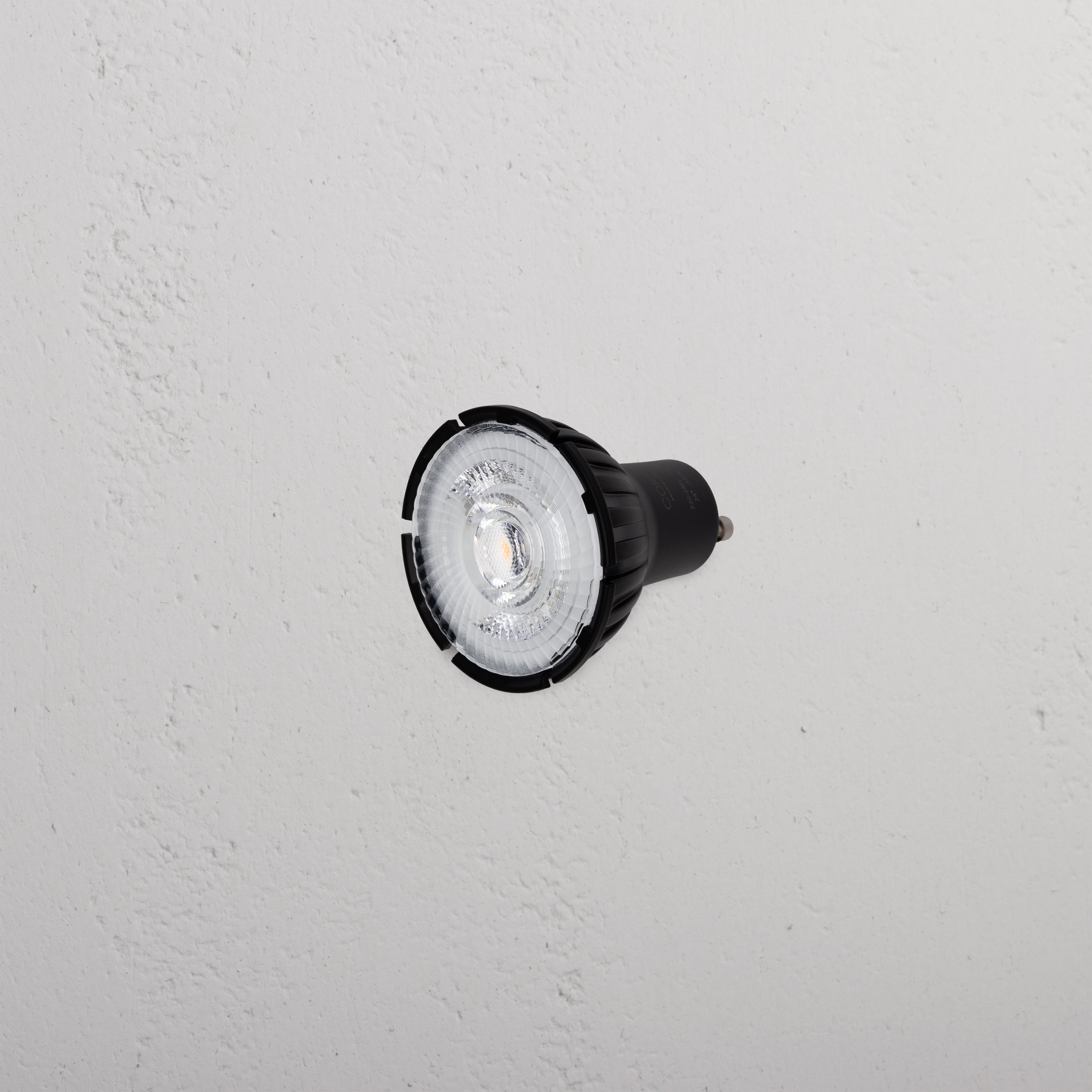 Arthur 50mm Black GU10 LED Bulb, 24° beam angle, on a textured white wall.