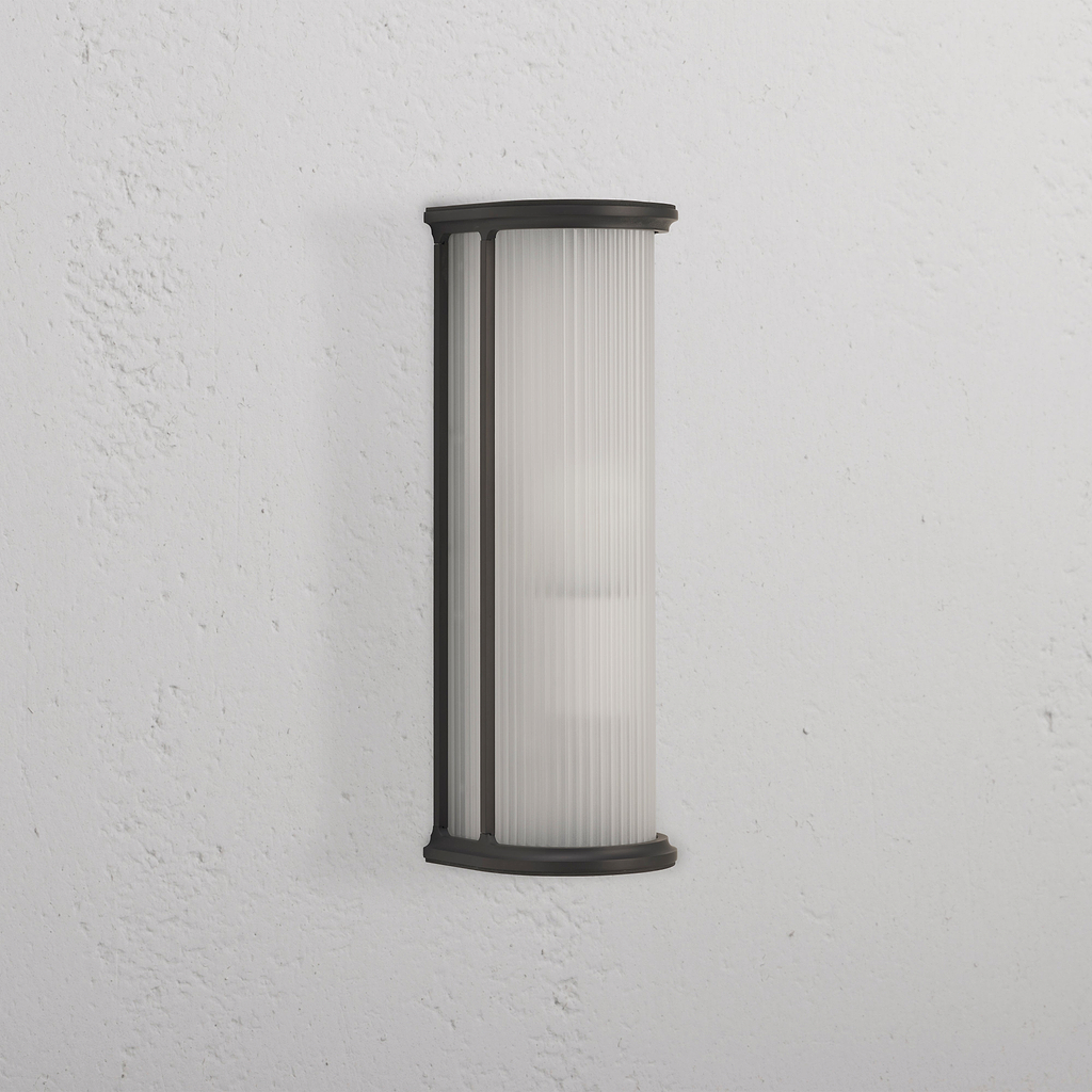 Medium Bank Wall Light Fluted Glass in bronze finish with fluted frosted glass shade, mounted on white wall.
