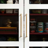 Antique brass Sycamore Furniture Handle, 224mm, medium pull handle mounted on a kitchen cabinet.