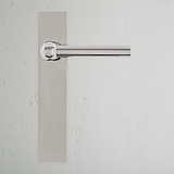 Harper Long Plate Sprung Door Handle in polished nickel on a white textured wall.