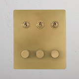 Antique Brass 6G Switch panel with three round dimmers, model 3T3D, mounted on a white wall.