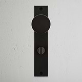 Bronze Onslow Long Plate Sprung Door Knob & Thumbturn on a textured white wall.