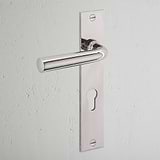 Polished Nickel Apsley Long Plate Door Handle & Euro Lock with keyhole on a white textured wall.