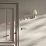 Malvern Small Wall Light in Pleated Alabaster White and Polished Nickel, softly illuminating a wall.
