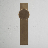 Onslow Long Plate Fixed Door Knob in Antique Brass with an elegant, timeless design on a textured white background.