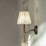 Medium Malvern Wall light in Alabaster White at an angle affixed to a wall and turned on
