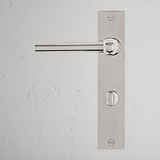 Harper Long Plate Sprung Door Handle & Thumbturn in Polished Nickel on a white textured wall.