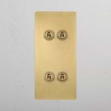 Antique brass 4G vertical toggle switch for light control, on a white textured wall.