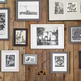 Antique brass and black double socket fixed to wooden slatted wall with various sized framed pictures