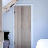 Clear toggle light switch on white wall with wooden door
