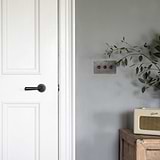 bronze 3 gang toggle light switch next to white door with door handle