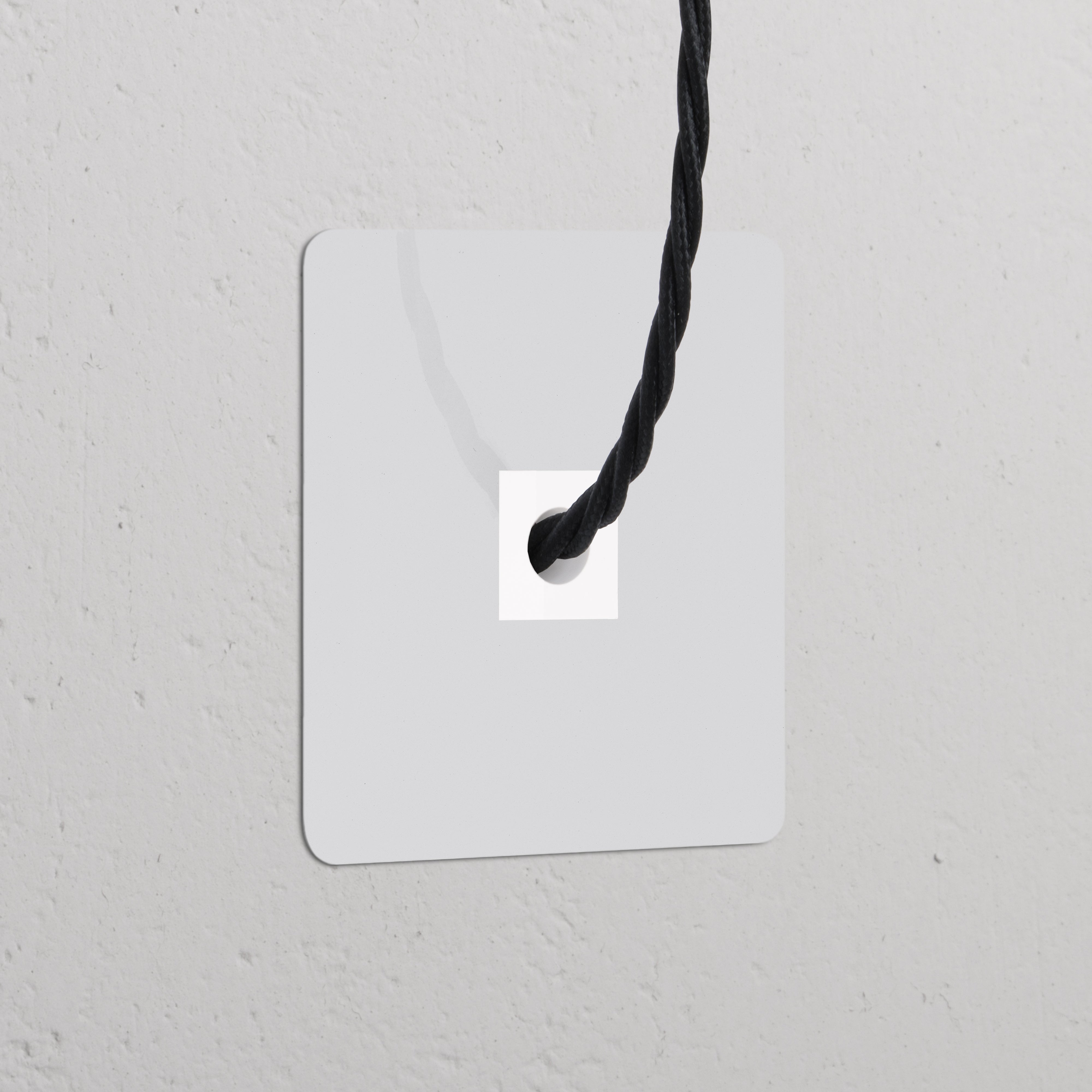Einfachrahmen mit Kabelausgang – Lackierbar + Weiß, ideal für Steckdosen und Module, an einer strukturierten Wand.