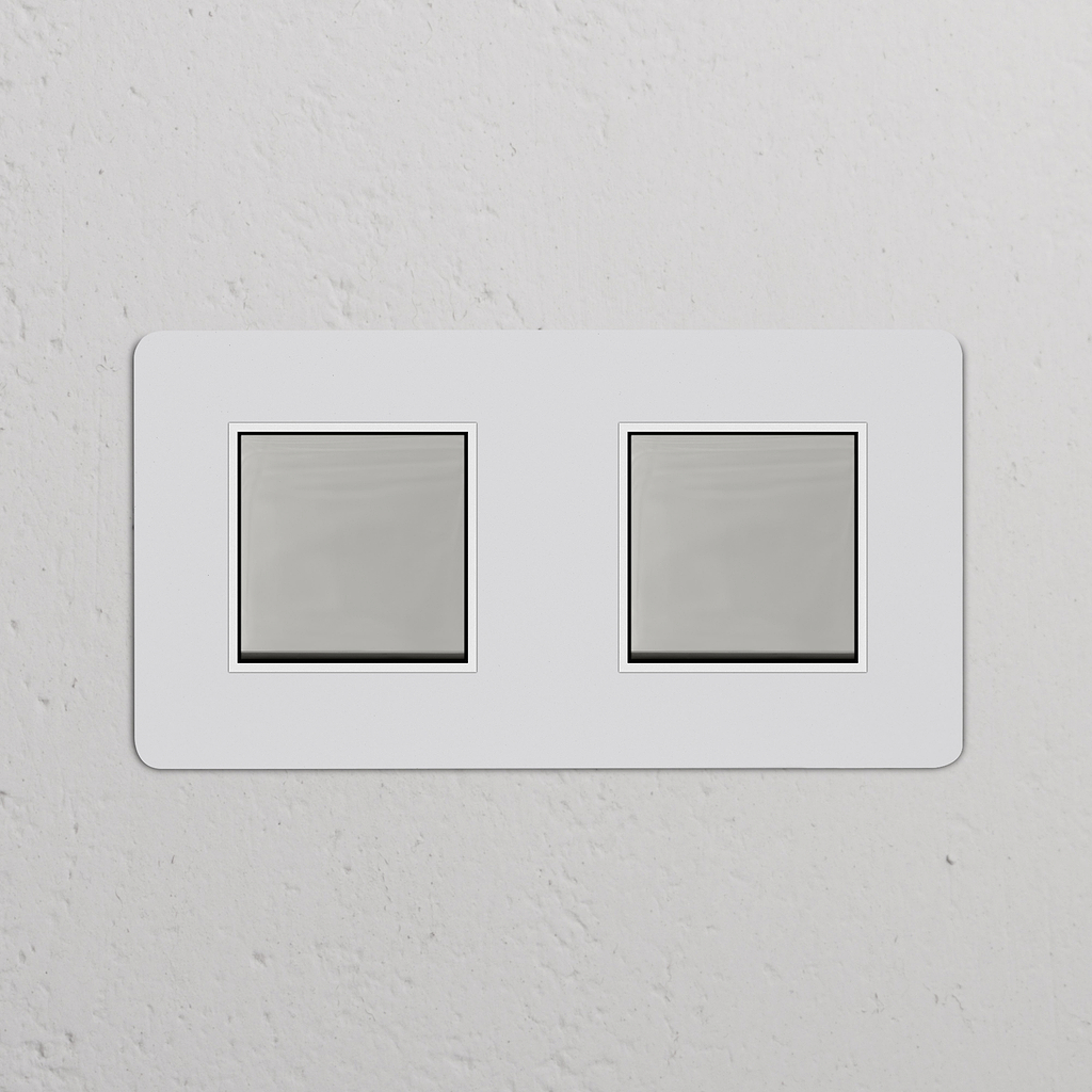 Zweifachrahmen mit 2x Wippschalter – lackierbar, poliertes Nickel, weiß – auf einer weißen Wand montiert.