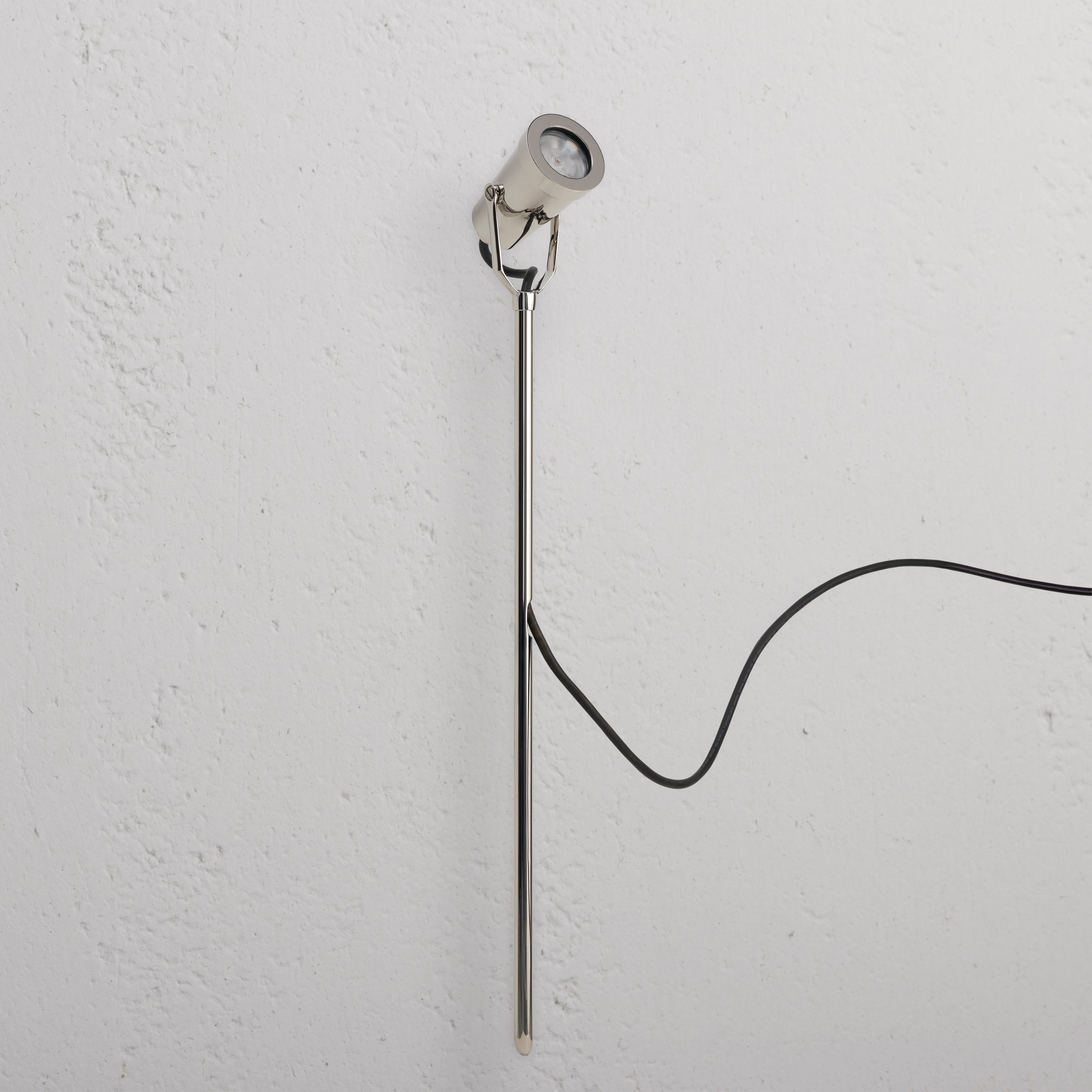 Cambridge Bodenstrahler Ã¢â‚¬â€œ poliertes Nickel Outdoorstrahler, montiert an einer weiÃƒÅ¸en Wand mit schwarzem Kabel.