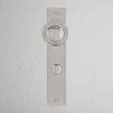 Poliertes Nickel-Pappel-Türknauf mit langem Schild und Drehknopf auf weißer Texturwand.