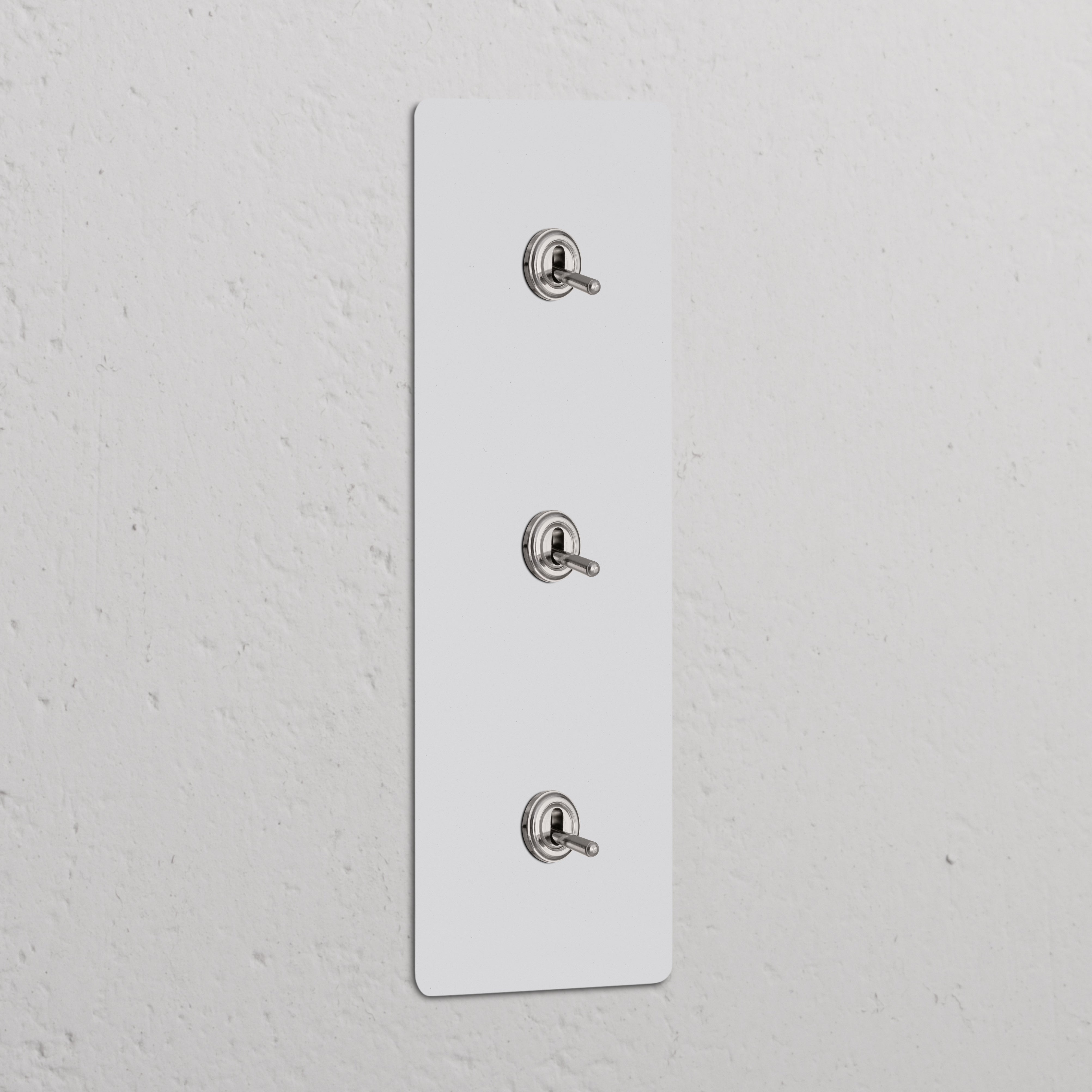 Schlanker vertikaler Dreifachrahmen mit 3 Kippschaltern, lackierbarem Finish + Akzenten aus poliertem Nickel.