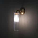 Antikes Messing fixe Wandleuchte mit Schirm aus geriffeltem Glas an grauer Wand