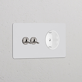 Zweifachrahmen mit 2 Kipphebelschaltern und Schuko-Typ-F-Steckdose, lackierbar in poliertem Nickel-Finish für die Wandmontage.