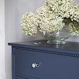 Tirador redondo Kilburn para muebles en níquel pulido sobre despensa azul