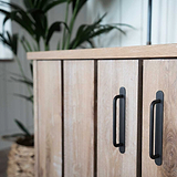 Tirador estilo barra para muebles Kilburn en bronce sobre despensa de madera