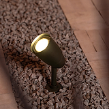 Lámpara para suelo Ealing en bronce iluminando hacia arriba desde una base de piedra por debajo. 