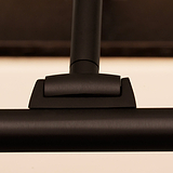 Primer plano de una elegante bisagra de metal negro, que irradia la sofisticación de las luces para cuadros de bronce Harrow de 220 mm. 