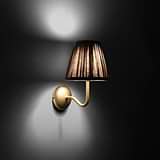 Aplique de pared Malvern pequeño en beige natural colocado en ángulo y encendido, de noche