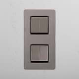Interruptor para control de la luz de alta capacidad en diseño vertical sobre fondo blanco: Interruptor doble de balancín x4 en níquel pulido y negro con diseño vertical