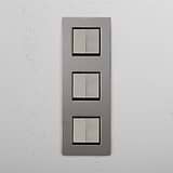 Interruptor para control de la luz de súper capacidad en diseño vertical: Interruptor triple de balancín x6 en níquel pulido y negro vertical sobre fondo blanco