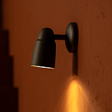 Lámpara de techo Ealing en bronce iluminando hacia abajo en una pared de piedra terracotta.