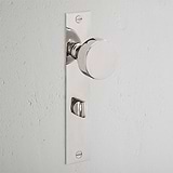 Pomo de puerta Onslow con placa larga y mecanismo de resorte en níquel pulido, montado en pared blanca.