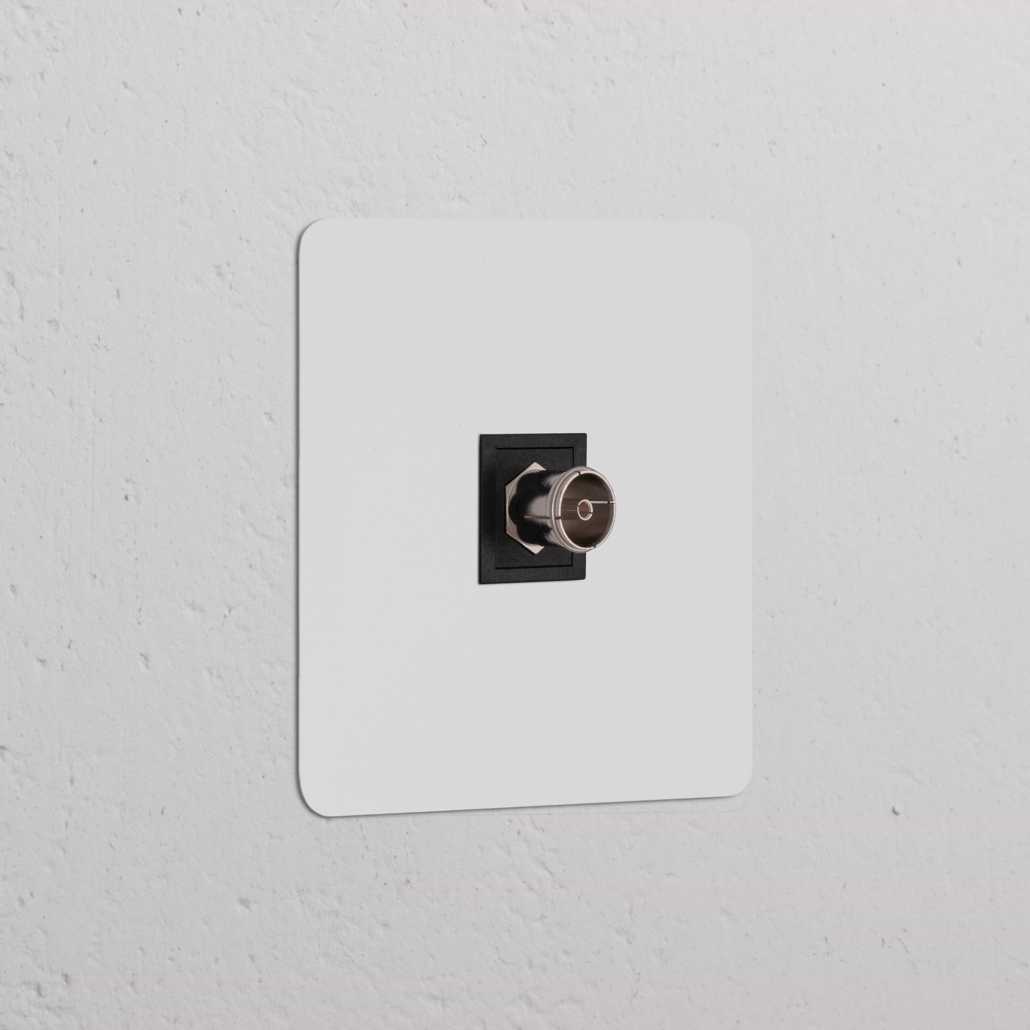 Toma TV (marco individual) pintable, inserción negra, enchufe de marco individual en pared blanca texturizada.