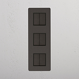 Interruptor triple de balancín en bronce y negro con diseño vertical, de alta capacidad - Solución avanzada para control de luces, sobre fondo blanco