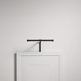 Una luz de cuadro Bronce Harrow de 220 mm ilumina una barra de ropa situada encima de una puerta de madera blanca en una pared sencilla.