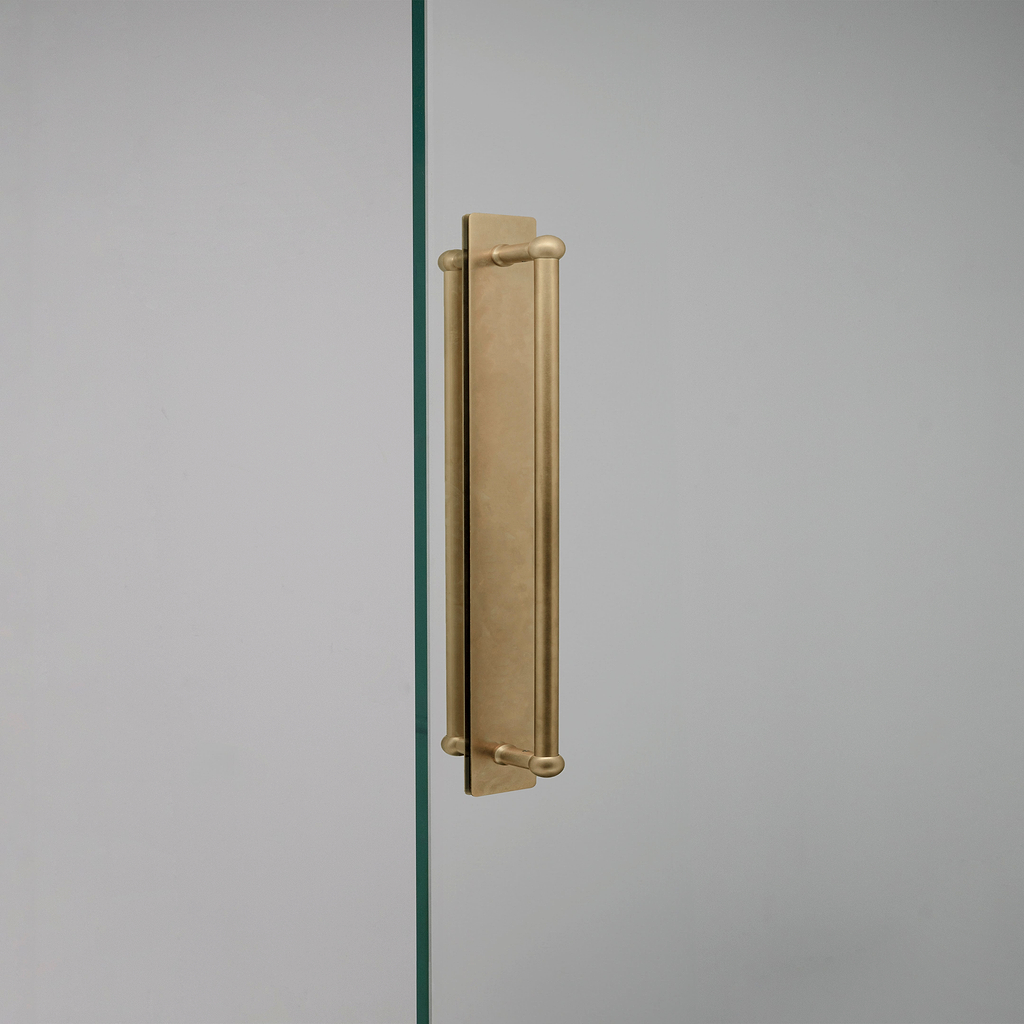 Tirador doble para puertas Harper con placa en latón antiguo de 320mm sobre fondo blanco