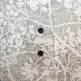 Interruptores dobles verticales, transparentes/bronce, en marco doble sobre fondo de papel pintado floral.