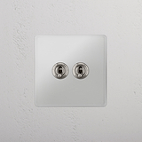 Interruptor doble de palanca en níquel pulido y traslúcido, eficiente - Accesorio superior para control de la luz, sobre fondo blanco