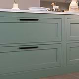 Tirador Oxford en bronce, de 384mm colocado en un cajón de mueble de cocina bajo encimera. Mostrando cajones verdes con mármol blanco. 