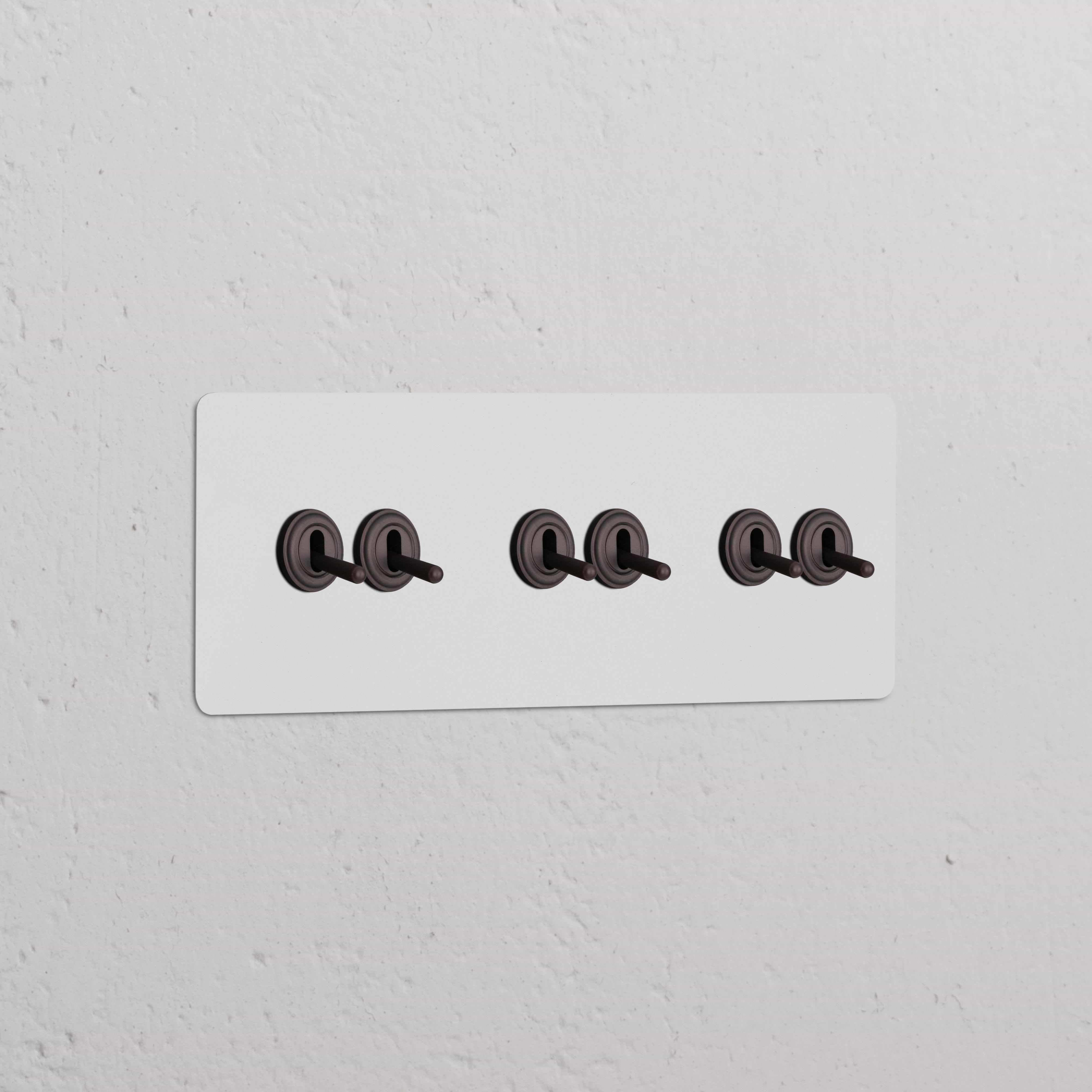 Interrupteur Peignable en bronze VV à Levier x6 sur plaque triple, monté sur un mur texturé.