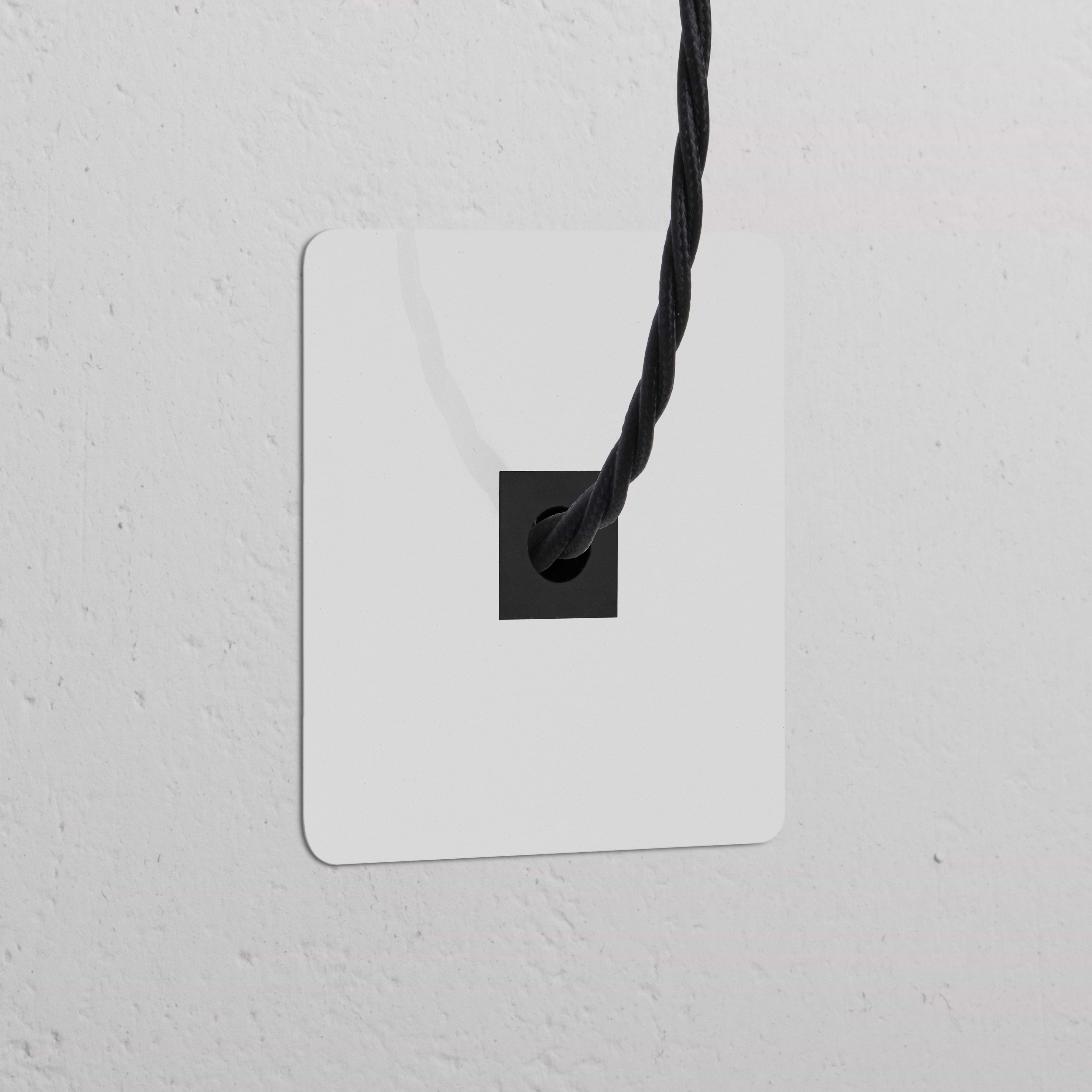 Sortie de Câble (Plaque Simple) - Peignable Noir, une sortie de câble noire sur un mur blanc texturé.