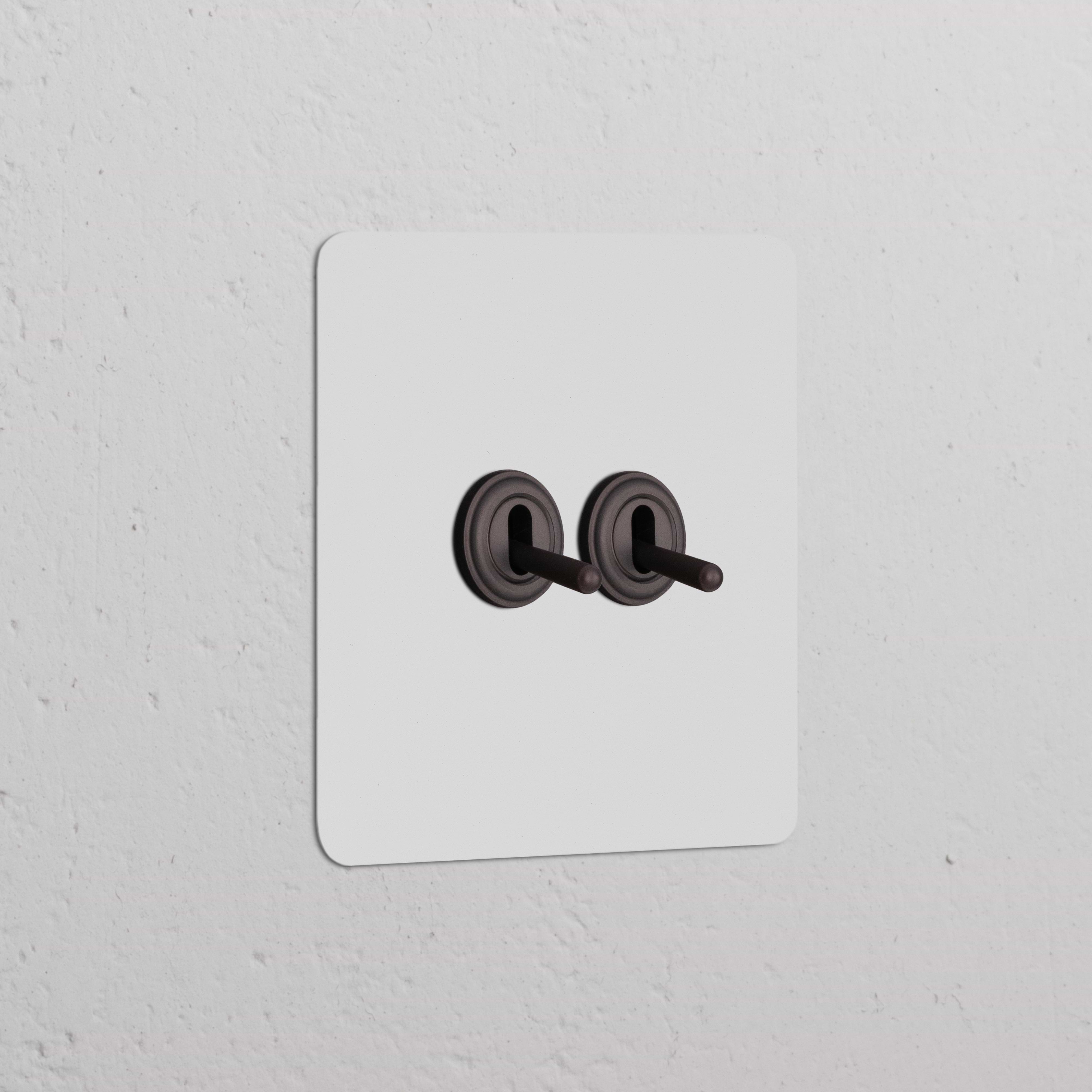 Interrupteur VV à Levier x2 (Plaque Simple) - Bronze Peignable sur un mur blanc, design classique et fonctionnel.