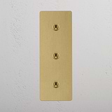 Antique Brass Triple Toggle Switch with Vertical Orientation on White Background