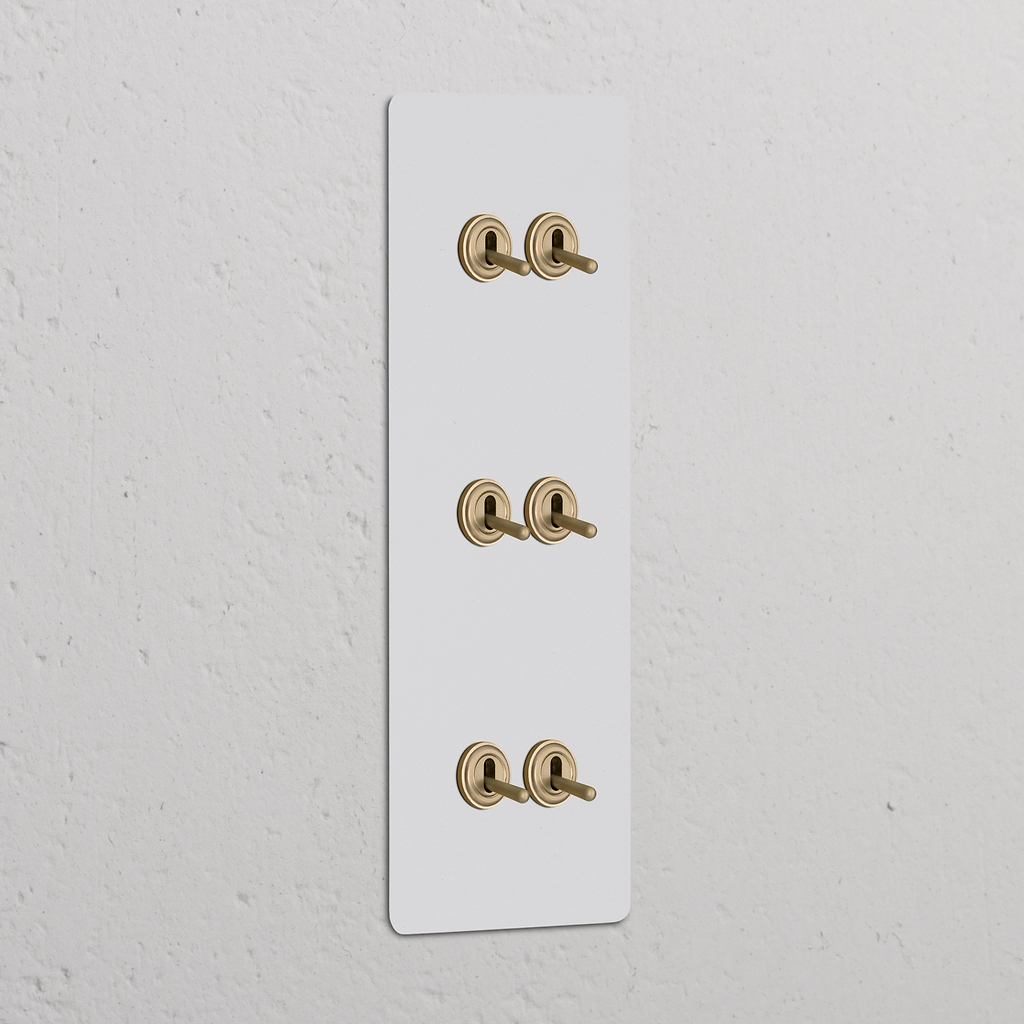 Primo piano di un interruttore a tripla levetta verticale con finitura in ottone anticato, compatibile con placche a muro verniciabili.