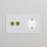 Interruttore a levetta doppio bianco e modulo di alimentazione Schuko tipo F a parete, finitura ottone anticato, verniciabile.
