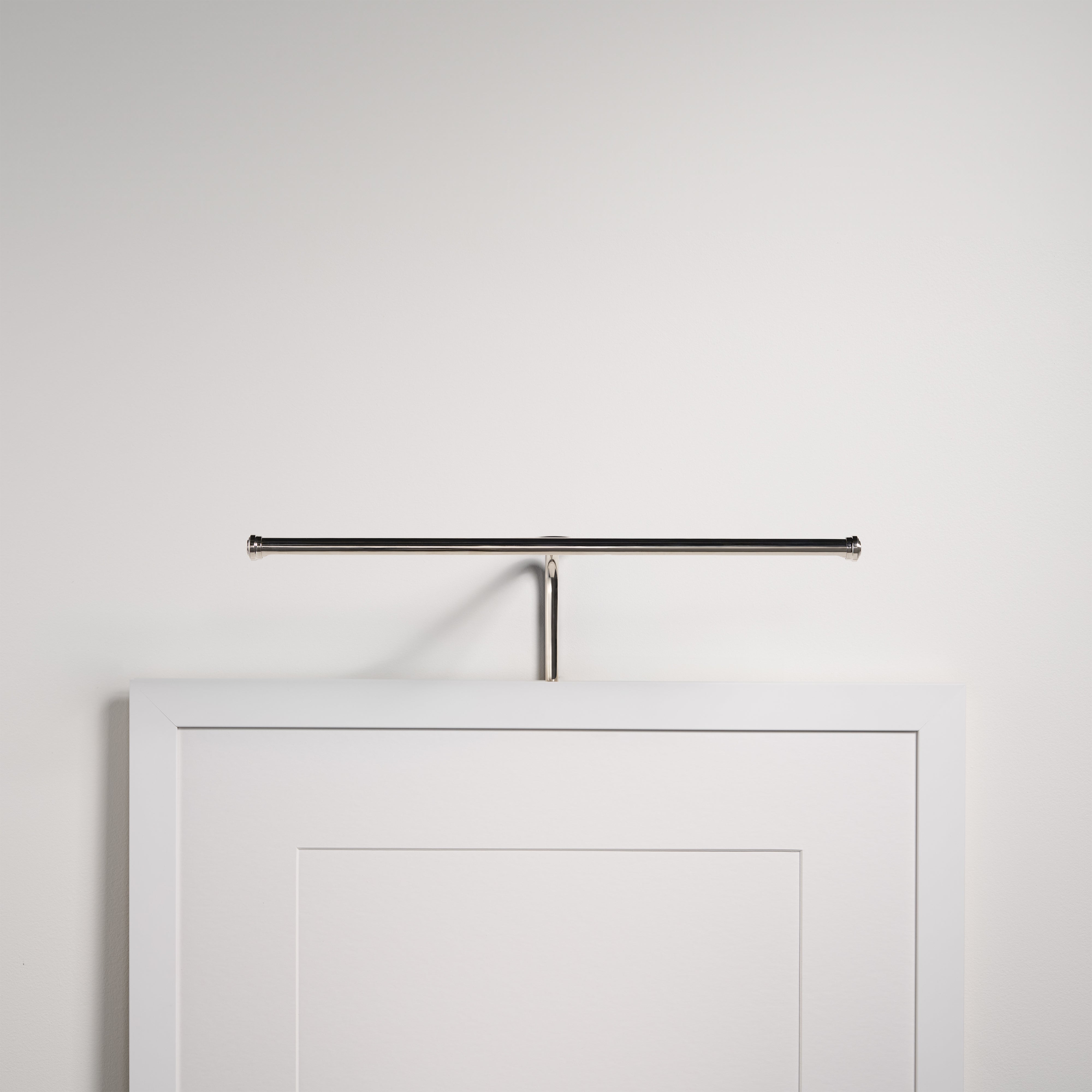 Applique per quadri Harrow da 400 mm in finitura Nichel Lucido, che valorizza con eleganza una cornice bianca sulla parete.