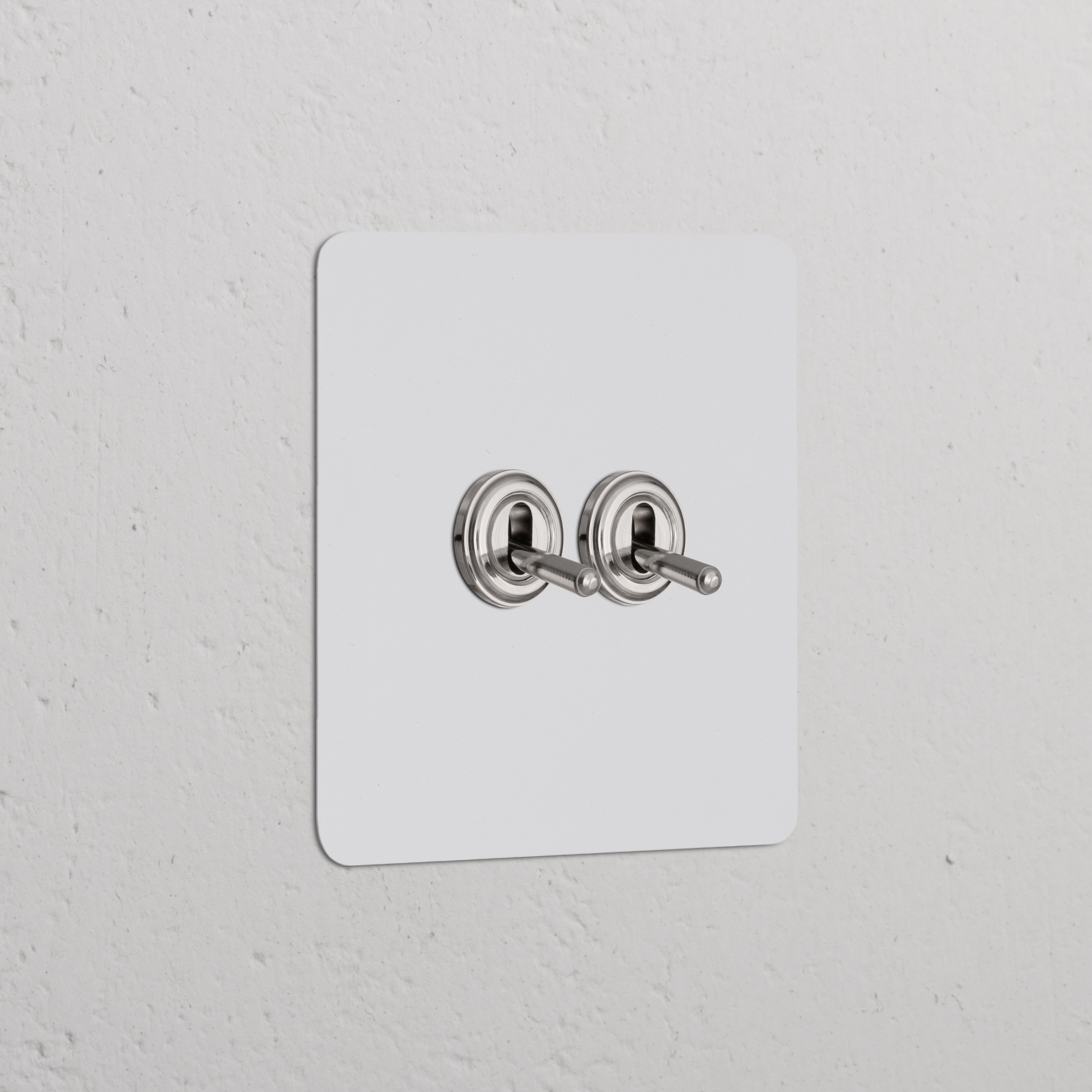 Elegante Interruttore a Levetta Singolo 2x in Pitturabile Nichel Lucido su una parete bianca minimalista.