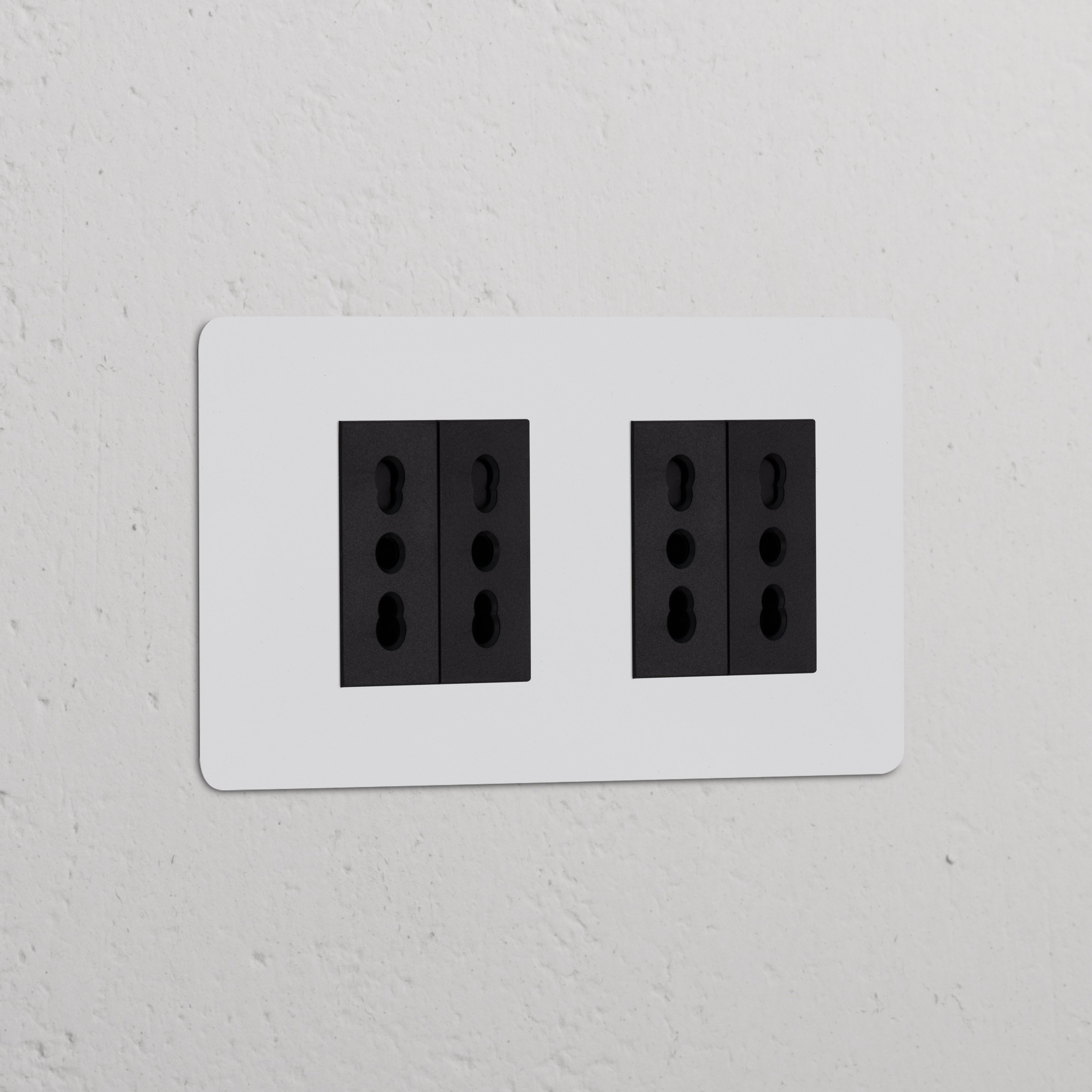 Prese doppie nere, Modulo di alimentazione Bipasso 4x Doppio, su parete bianca per collegamenti elettrici versatili.