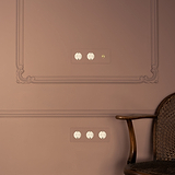 Triplo interruttore a levetta con finitura Ottone Antico Bianco e 2 moduli Schuko Tipo F su parete elegante.